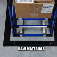 Un área cuadrada designada para materia prima está marcada con cinta de piso.