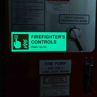 Una señal brillante en un cuarto oscuro que dice 'firefighter controls.'