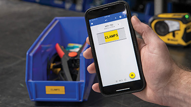 Una persona sosteniendo un teléfono. La pantalla del teléfono muestra una etiqueta amarilla brillante creada usando Etiquetas rápidas para móviles. En el fondo, hay un tubo de plástico con la etiqueta impresa.