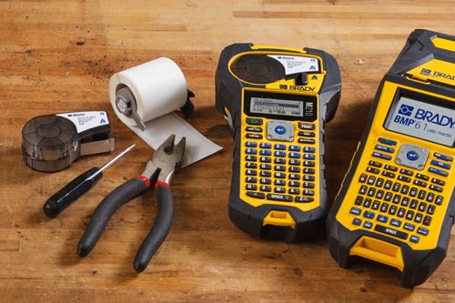 Dos cartuchos de etiquetas estándar junto a una impresora M210 y una M610