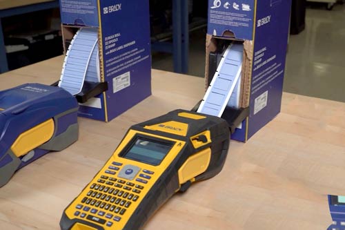 Una caja grande de etiquetas alimentando de forma continua una impresora de etiquetas M610