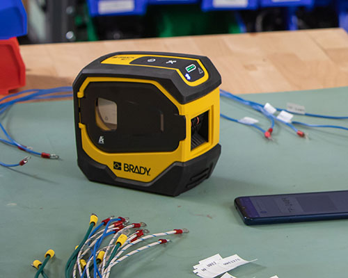 La impresora M511 con alambres etiquetados y un teléfono móvil.