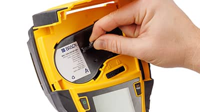 Un rollo de material de etiquetas siendo cargado en una impresora M410.